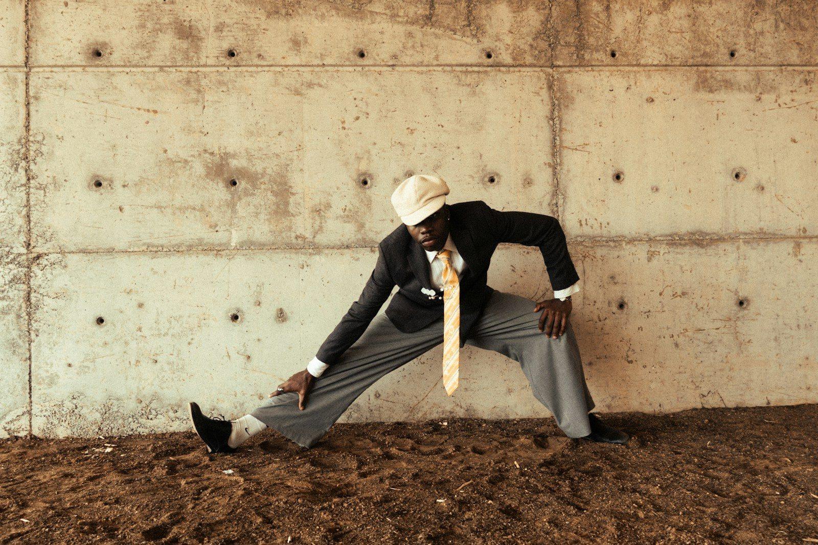 Man in suit stretching against concrete wall